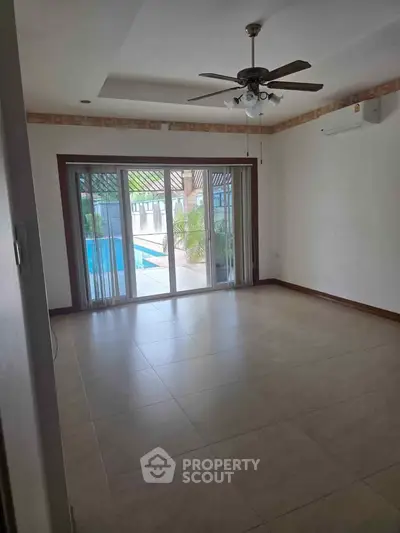 Spacious living room with pool view and ceiling fan in modern home