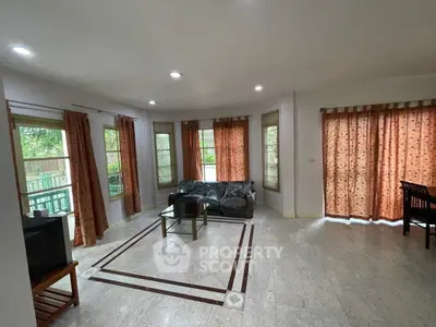 Spacious living room with large windows and elegant curtains, perfect for natural light.