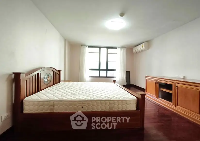 Spacious bedroom with wooden furniture and natural light