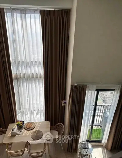 Elegant dining area with tall windows and balcony view, perfect for modern living.