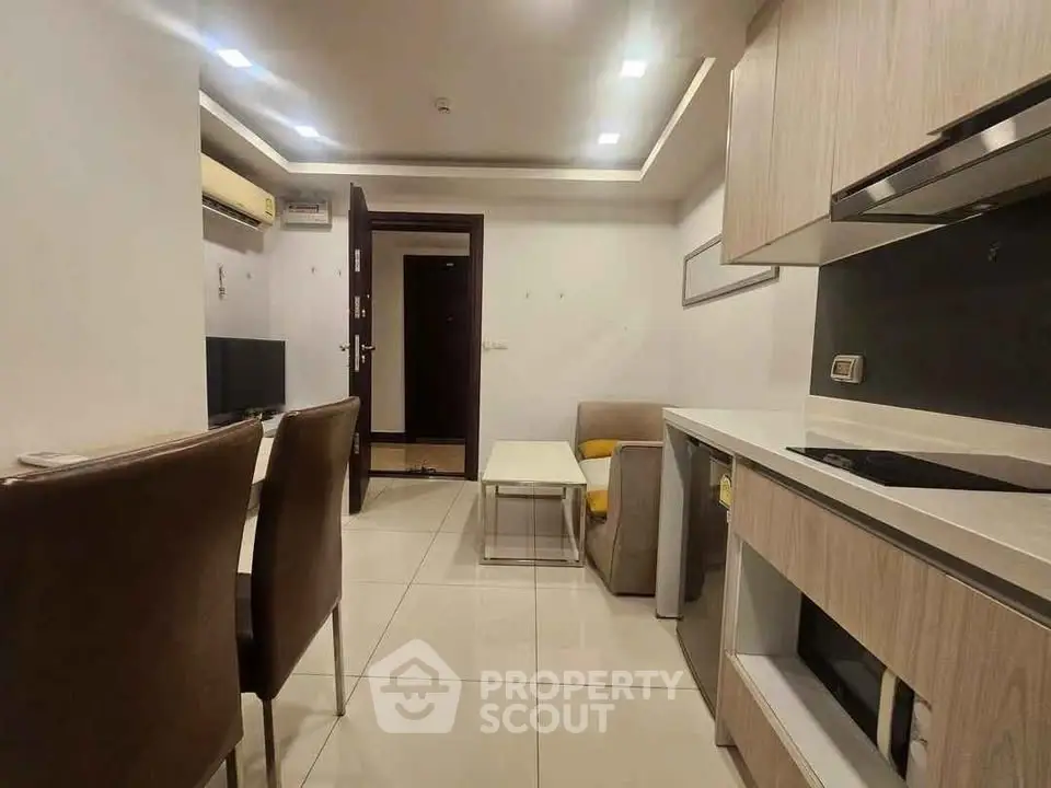 Modern open-layout living room with integrated kitchen, featuring sleek cabinetry and contemporary furnishings.