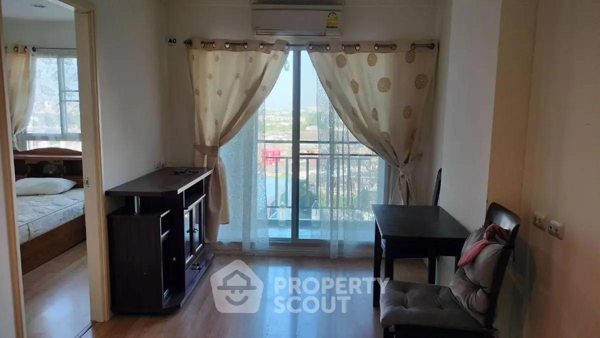 Cozy apartment interior with balcony view, featuring wooden flooring and elegant curtains.