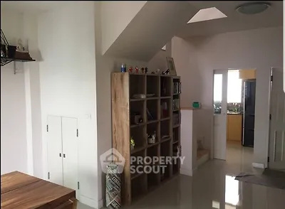 Modern living area with open shelving and kitchen view, featuring sleek design and natural light.