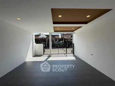 Spacious modern living area with large windows and stylish ceiling design, offering ample natural light and outdoor view.