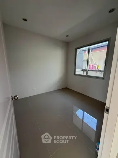 Spacious empty room with large window and glossy tiled floor