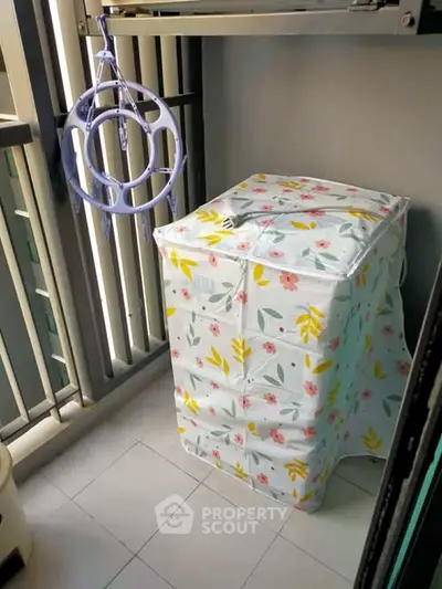 Compact balcony with covered washing machine and hanging laundry rack, ideal for urban living.