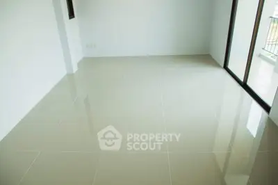 Spacious empty room with glossy tiled flooring and large windows