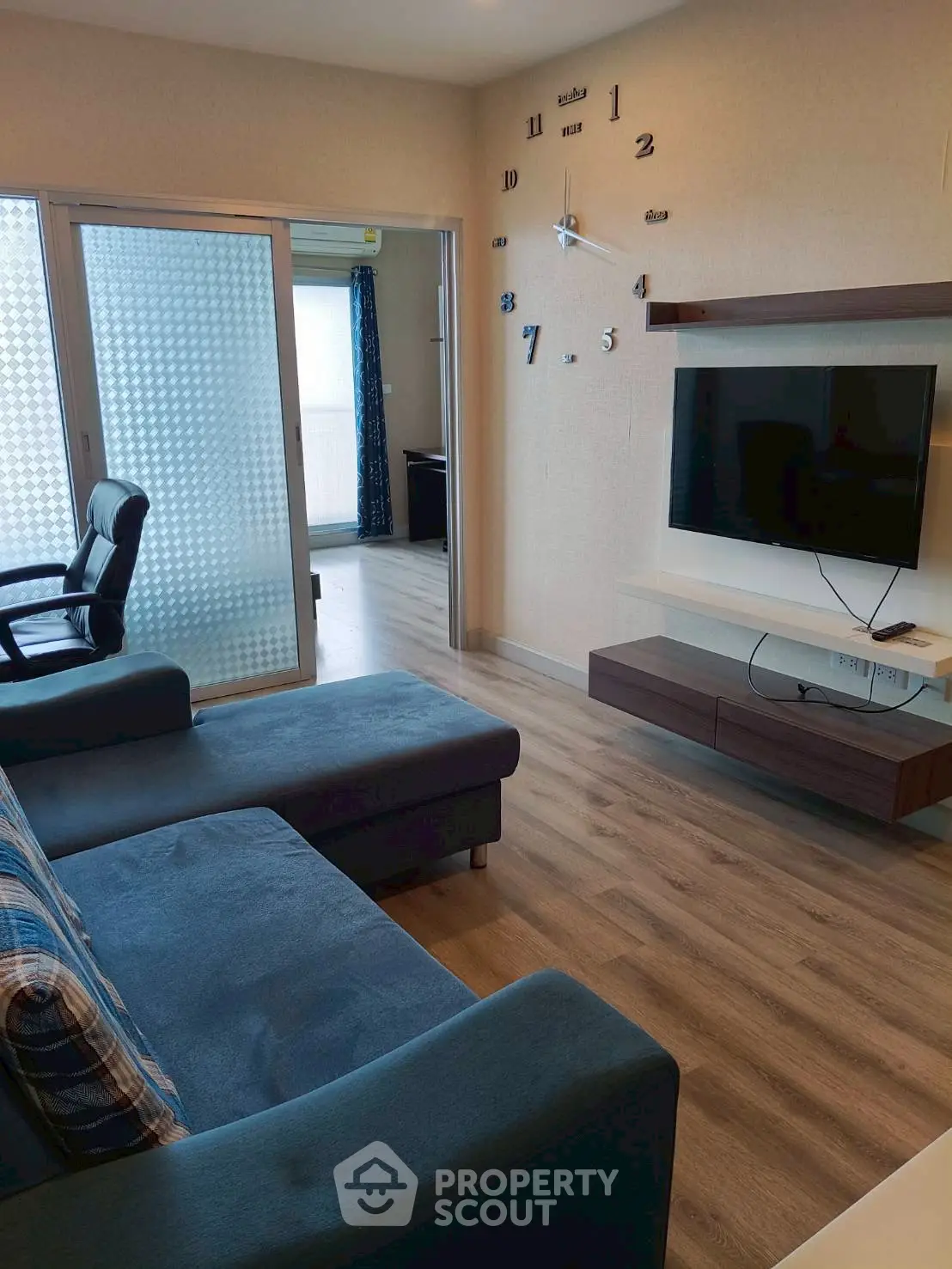 Modern living room with stylish decor and wall-mounted TV, featuring a cozy sofa and sleek wooden flooring.