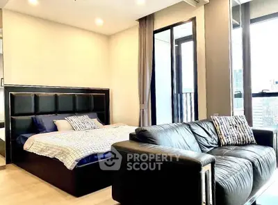Modern bedroom with stylish decor and city view, featuring a cozy bed and comfortable sofa.
