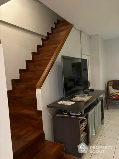 Modern living room with wooden staircase and sleek TV setup