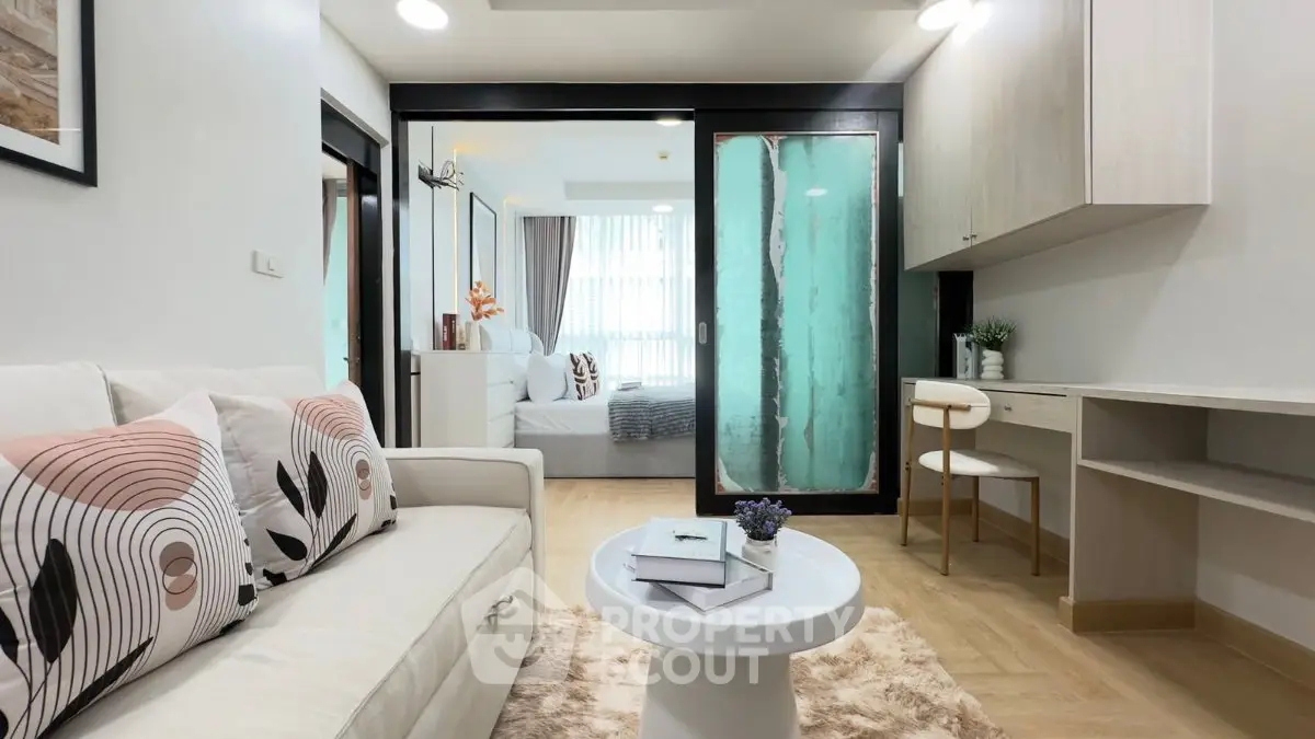 Modern living room with stylish decor and cozy ambiance, featuring a view into a chic bedroom.