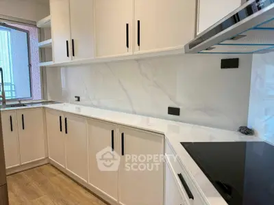 Modern kitchen with sleek white cabinets and marble backsplash, featuring an induction cooktop and ample counter space.