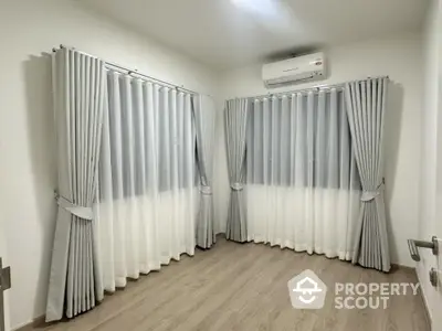 Bright corner room with elegant curtains and air conditioning, perfect for a cozy living space.