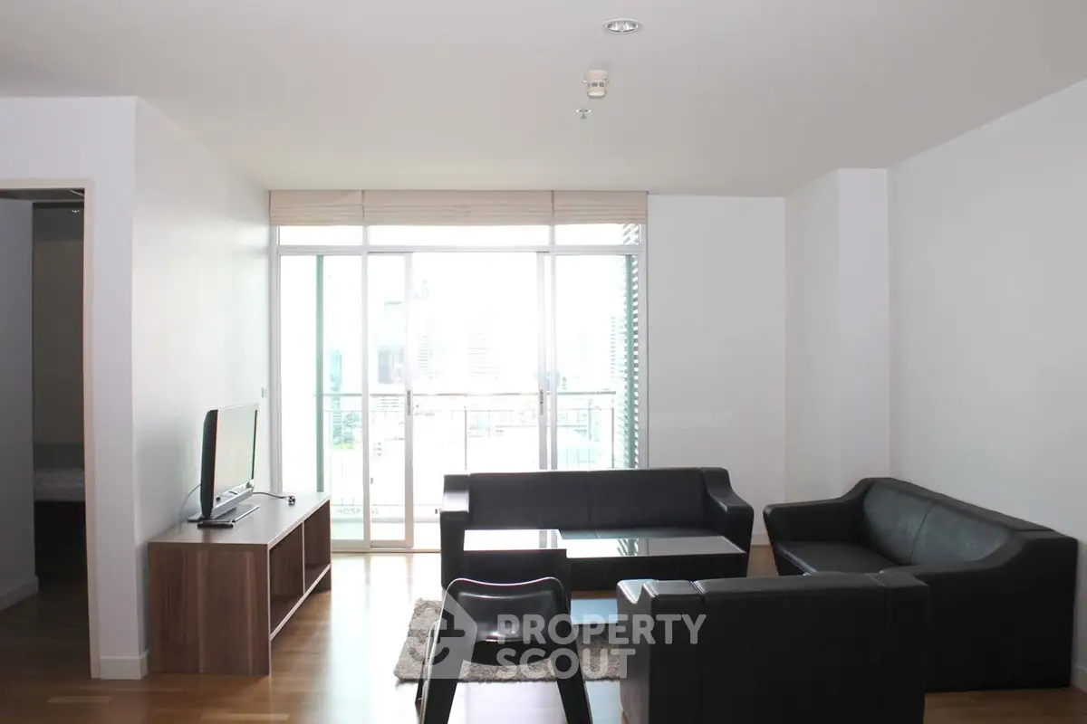 Modern living room with sleek furniture and large windows offering city views.