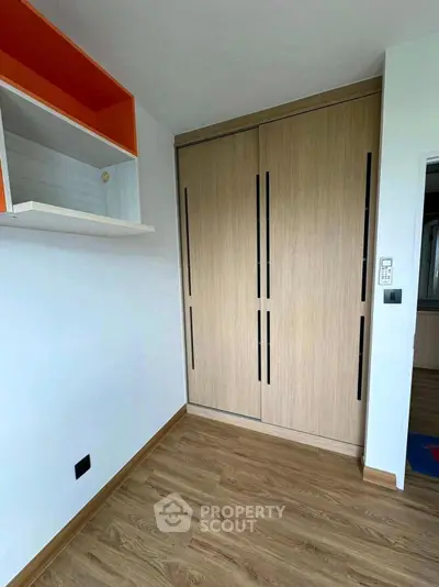 Modern bedroom with sleek wooden wardrobe and stylish shelving unit.