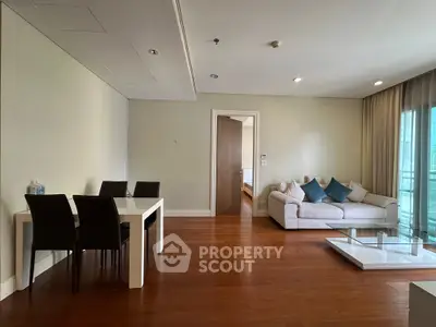 Spacious modern living room with elegant dining area and cozy seating, featuring wooden flooring and natural light.