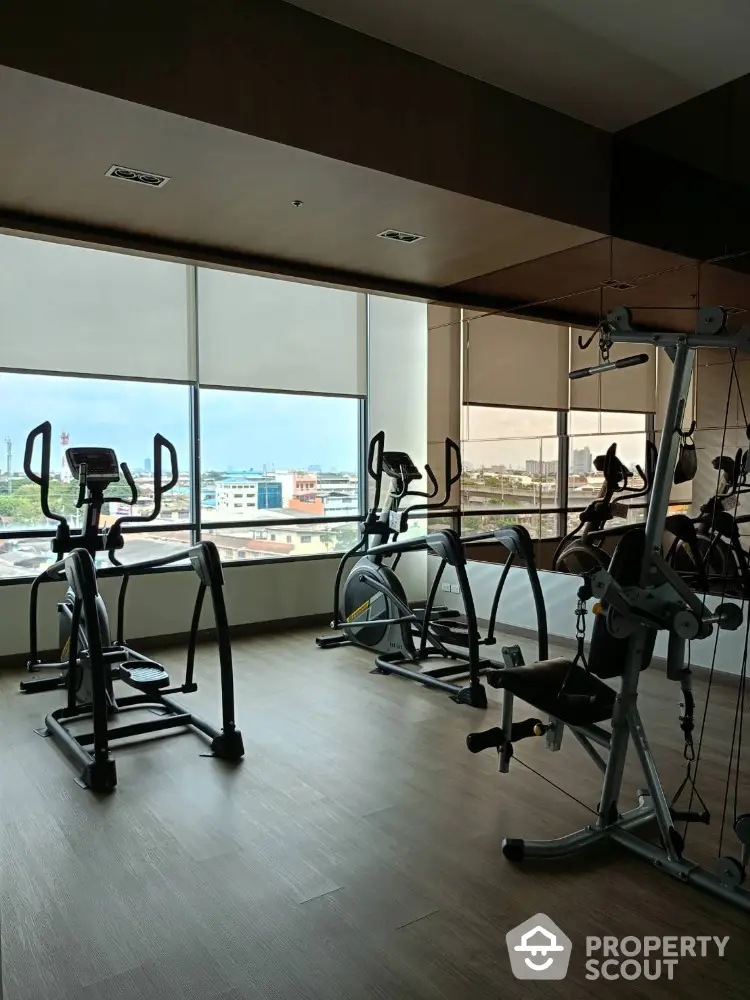 Modern gym with exercise equipment and city view from large windows