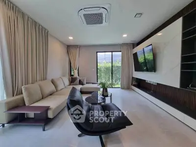Spacious modern living room with large sofa and wall-mounted TV, featuring elegant decor and natural light.