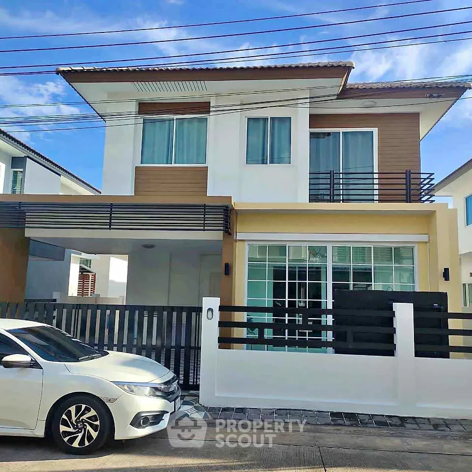 Modern two-story house with sleek design and large windows in a suburban neighborhood.