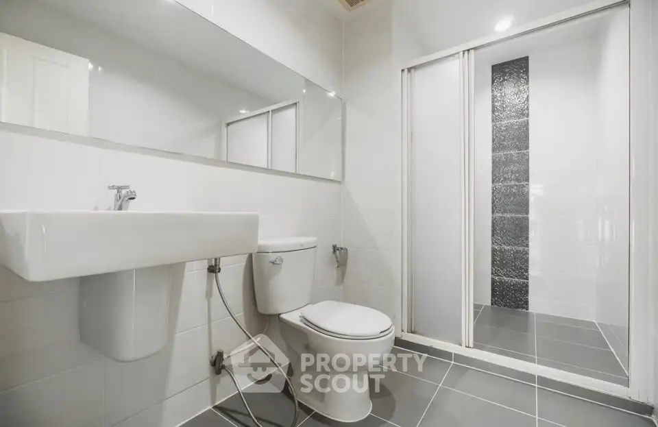 Modern bathroom with sleek design, featuring a spacious shower and elegant fixtures.