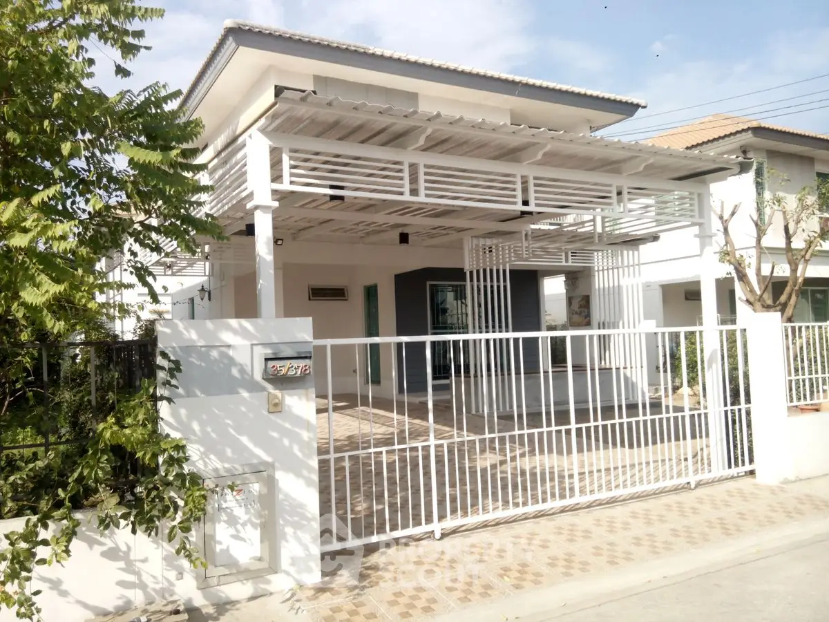 Modern white house with gated entrance and spacious driveway in a serene neighborhood.