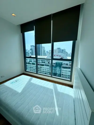 Bright bedroom with large windows offering stunning city views in modern apartment.