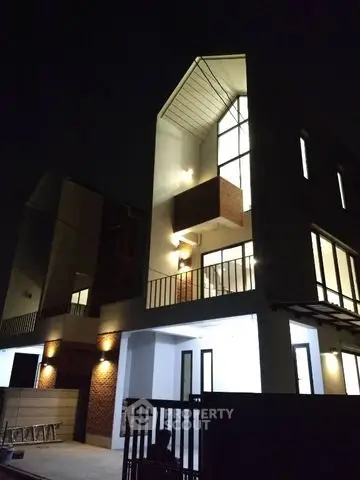 Modern architectural exterior with illuminated facade and large windows at night.
