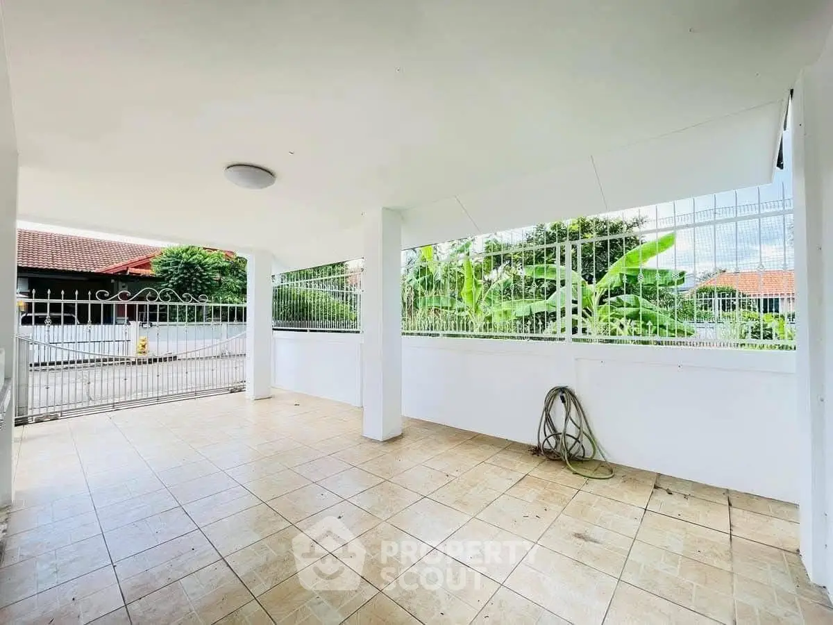 Spacious covered parking area with tiled flooring and gated entrance.