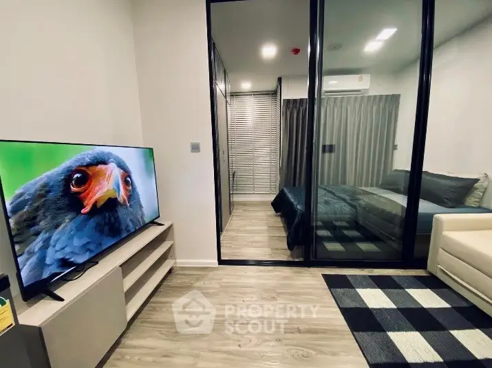 Modern living room with glass partition to bedroom, featuring sleek TV setup and stylish decor.