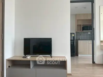 Modern apartment interior with sleek kitchen and cozy living area featuring a flat-screen TV.