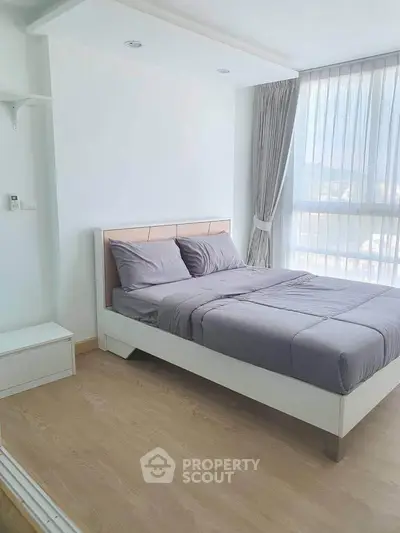 Modern bedroom with large window and stylish decor in a bright apartment.