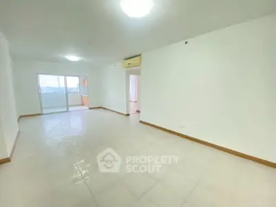Spacious unfurnished living room with balcony access and tiled flooring.