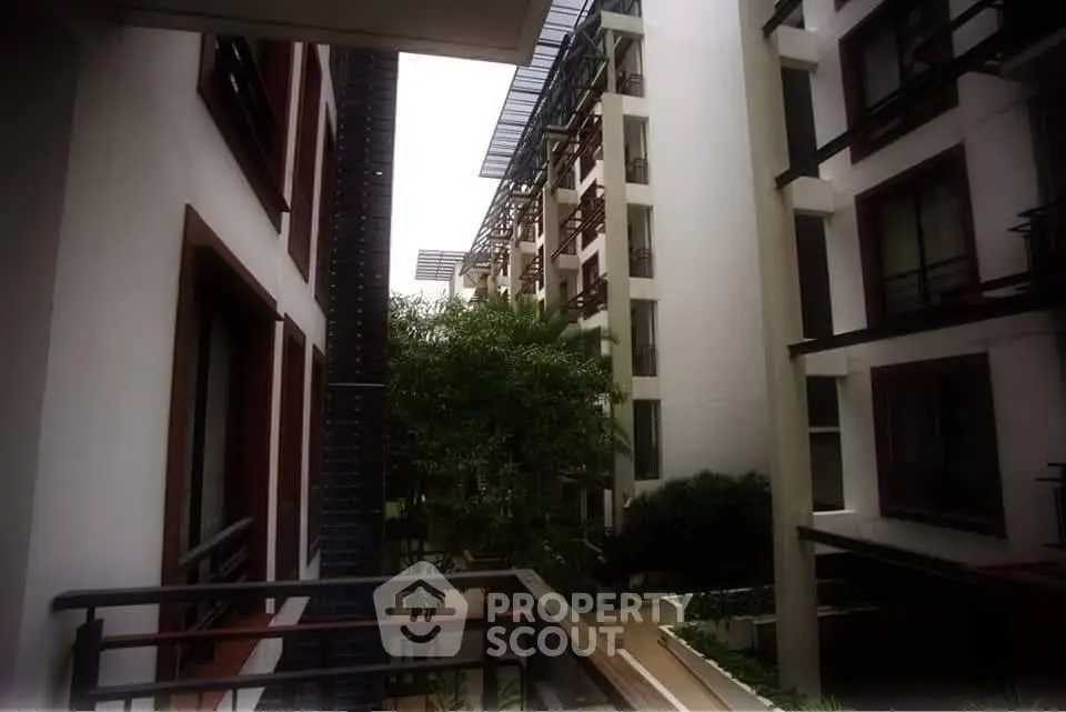 Modern apartment building exterior with lush greenery and sleek architectural design.