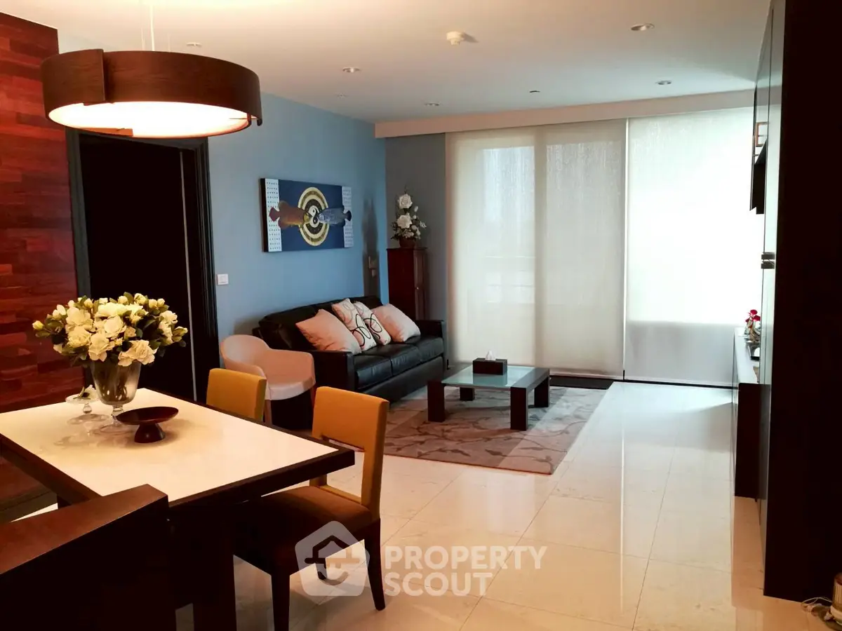 Elegant living room with modern decor and dining area, featuring stylish furniture and ambient lighting.