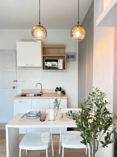 Modern kitchen with dining area, featuring sleek cabinetry and stylish lighting in a cozy apartment.