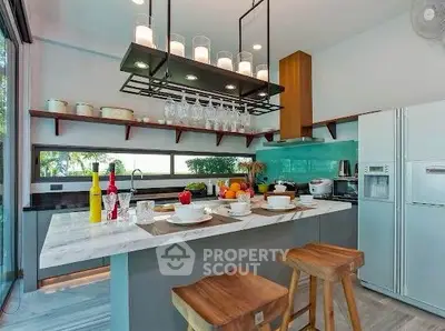 Modern kitchen with island, stylish lighting, and large windows offering a scenic view.