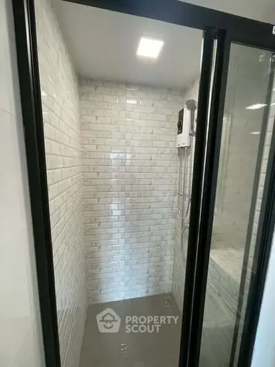 Modern shower area with sleek glass doors and white subway tiles.