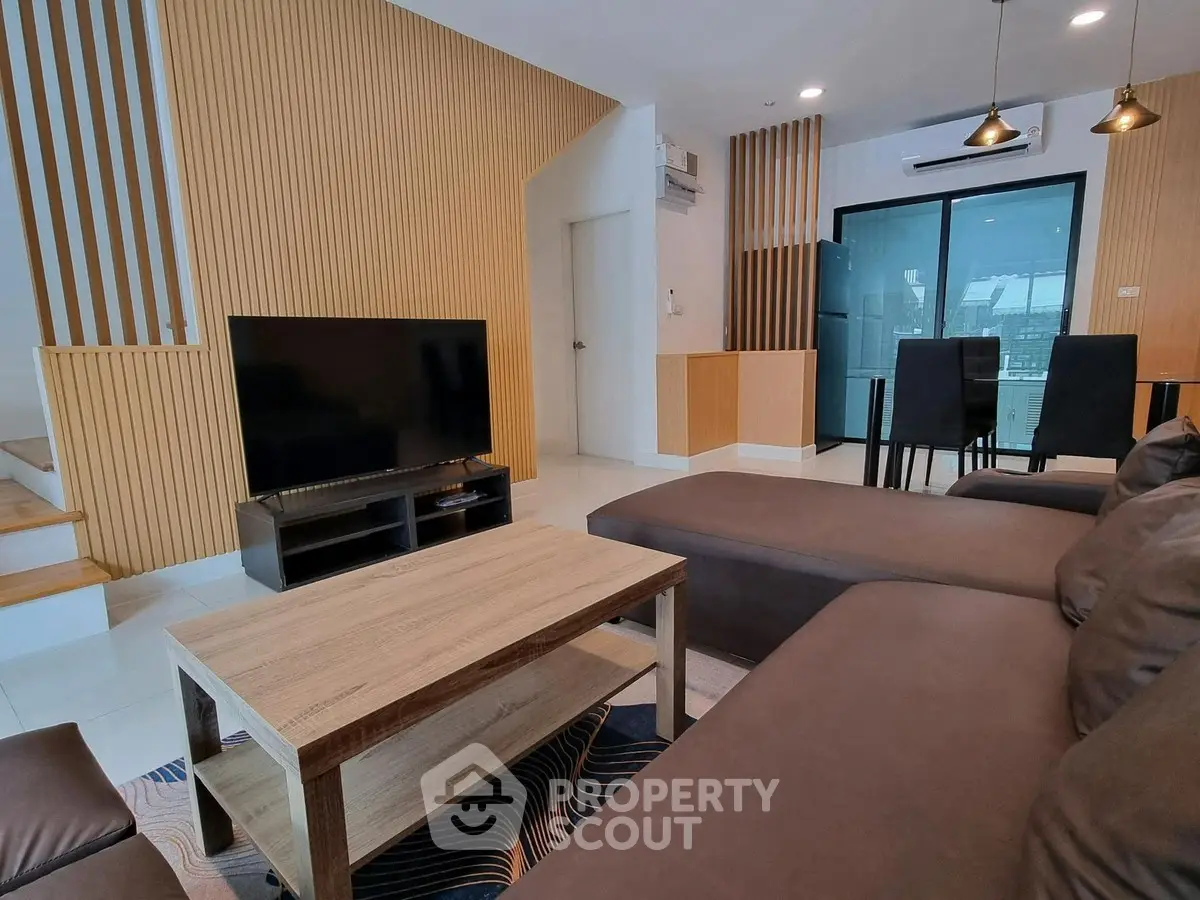 Modern living room with sleek furniture and open layout, featuring a stylish dining area and contemporary decor.