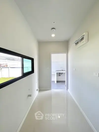 Bright hallway leading to a modern kitchen with sleek white finishes.