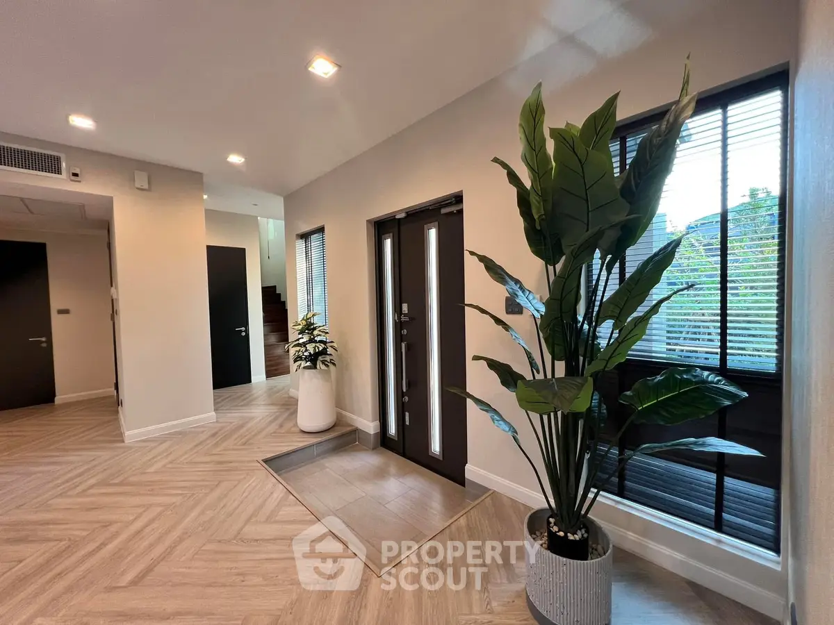 Elegant modern entrance with stylish flooring and large potted plants, showcasing contemporary design.
