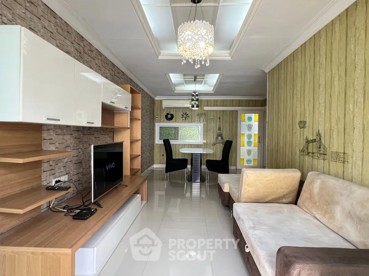 Modern living room with stylish decor and open dining area, featuring elegant lighting and contemporary furniture.