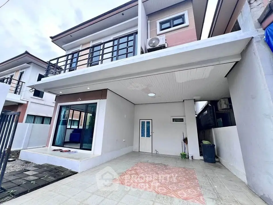 Modern two-story house with spacious carport and balcony, featuring sleek design and ample outdoor space.