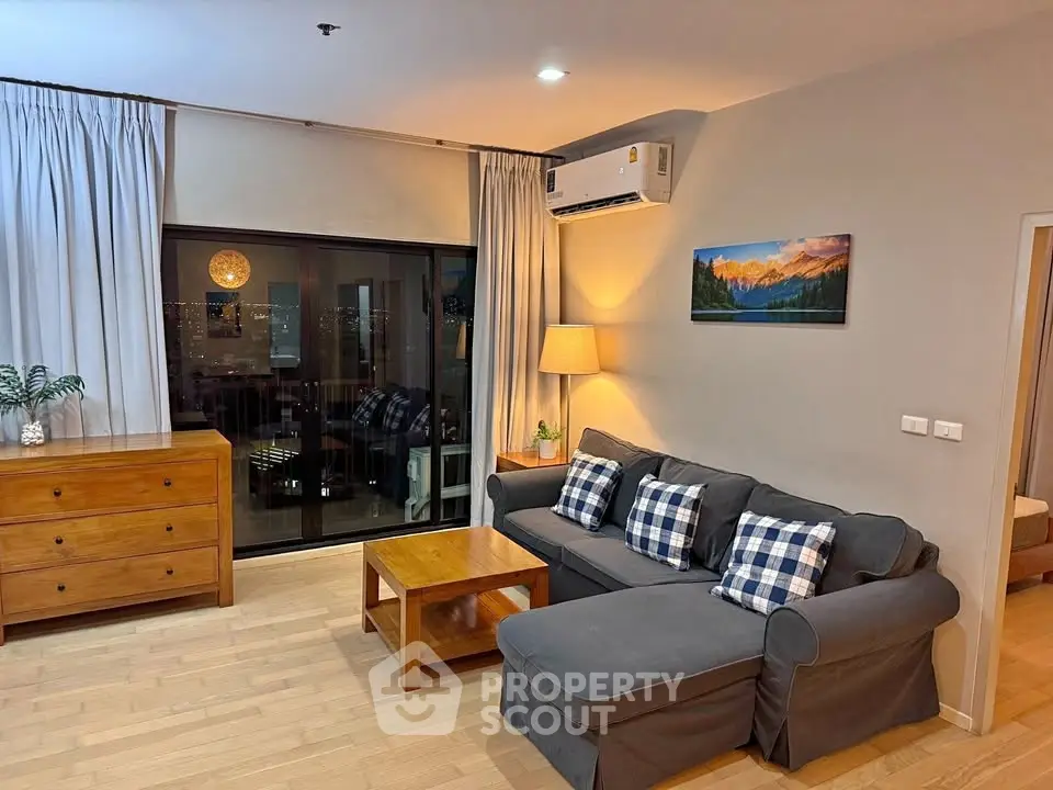Spacious living room with modern decor and city view, featuring a cozy sofa and elegant wooden furniture.