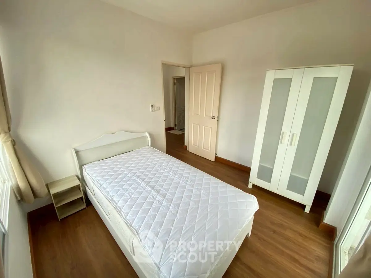 Cozy bedroom with single bed and wardrobe, featuring wooden flooring and natural light.