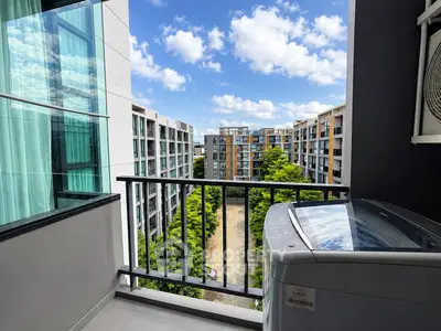 Modern apartment balcony with washing machine and scenic view of residential buildings.