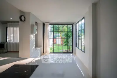 Bright and spacious living area with large windows and garden view, perfect for modern living.