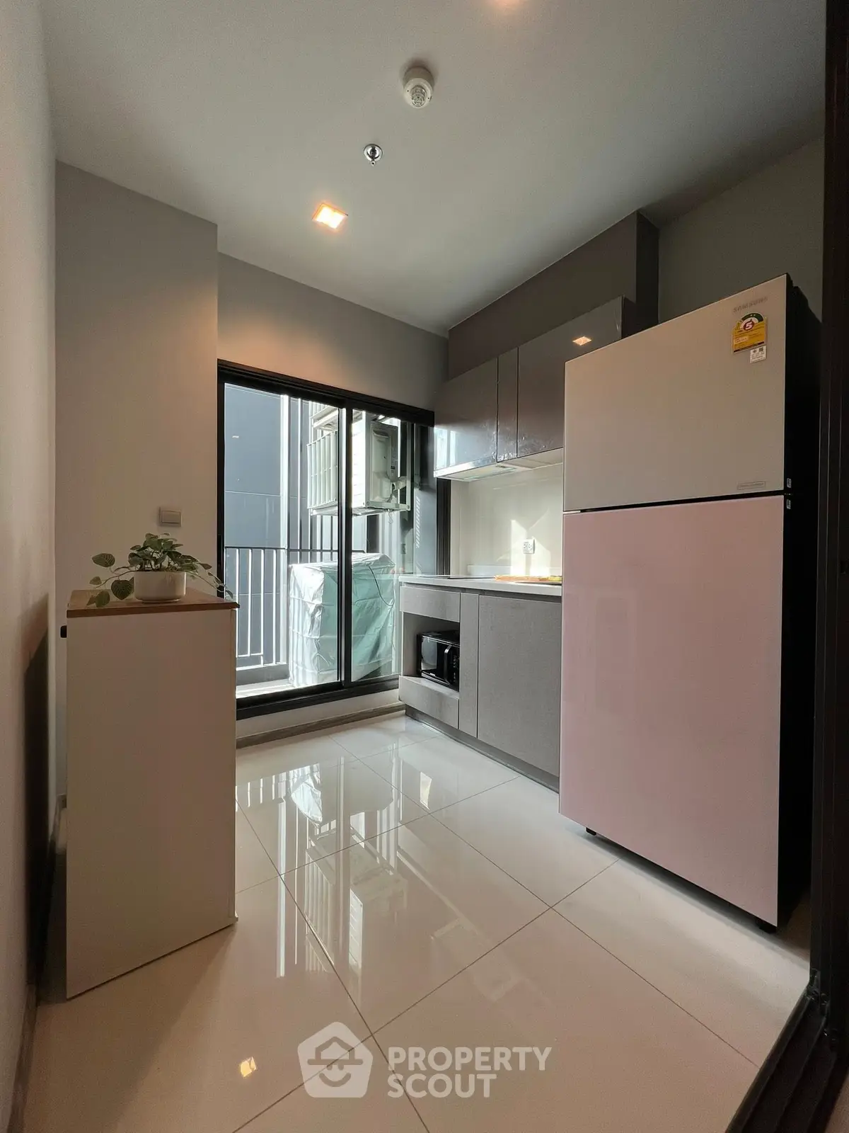 Modern kitchen with sleek design, featuring a large refrigerator and ample natural light.