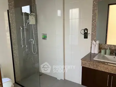 Modern bathroom with glass shower and elegant vanity in a stylish home.