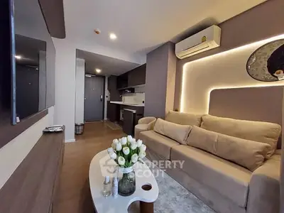 Modern living room with cozy beige sofa, stylish decor, and sleek open kitchen layout.