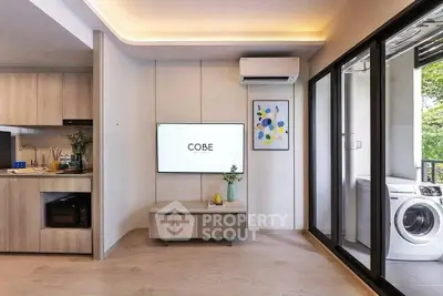 Modern living room with open kitchen and balcony featuring washing machine.